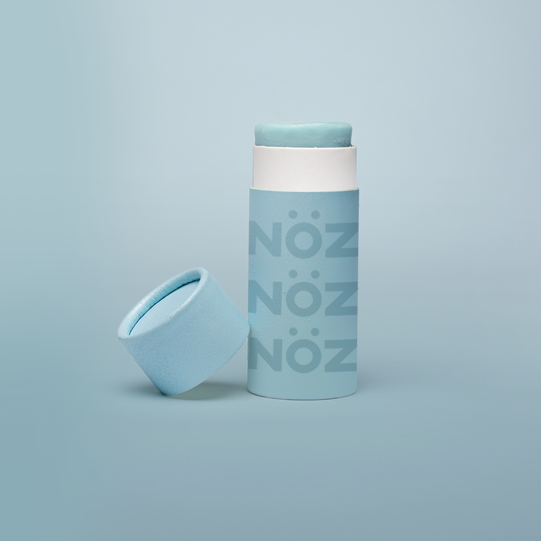 Blue Noz sunscreen standing with cap leaning on container