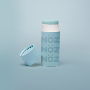 Blue Noz sunscreen standing with cap leaning on container