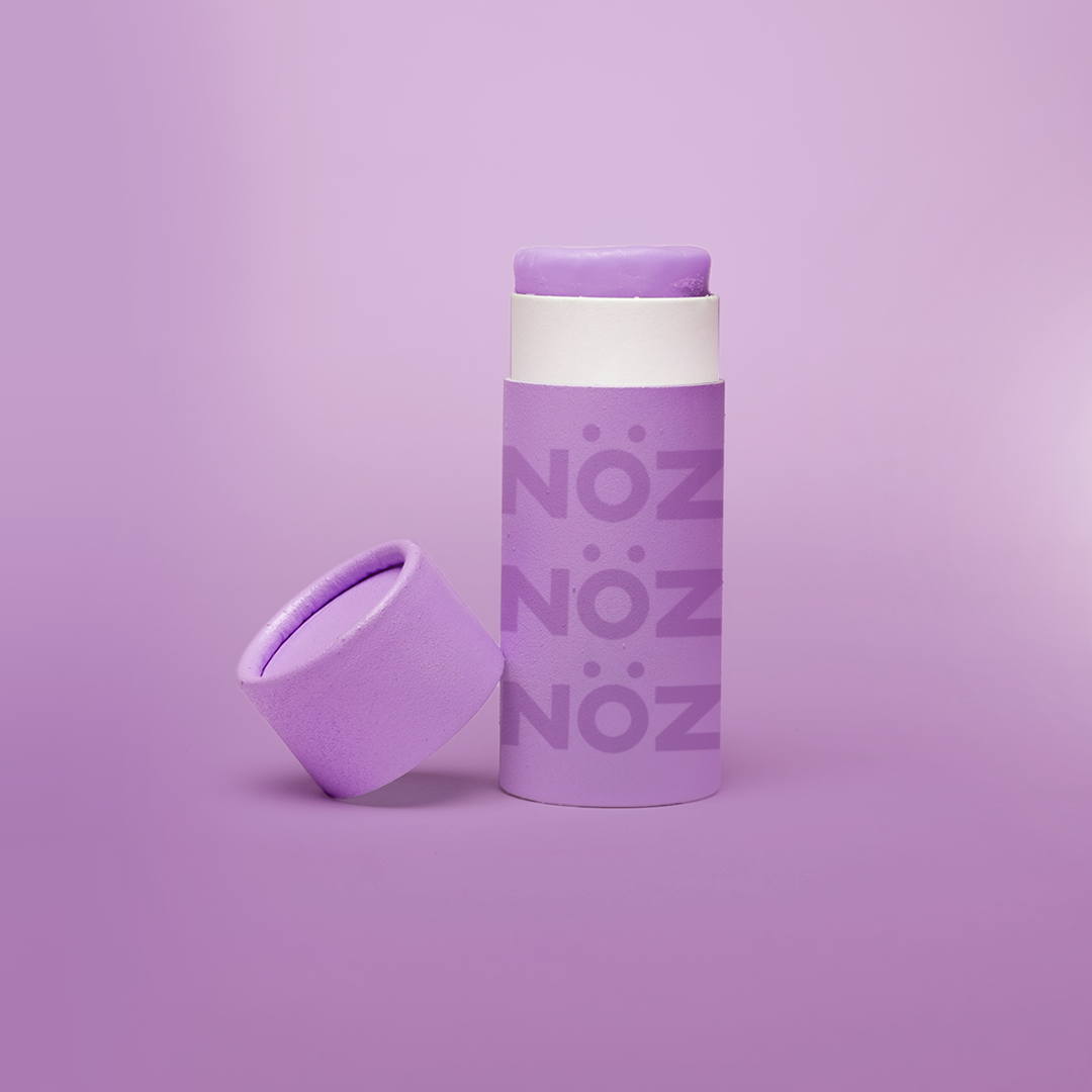 Purple Noz sunscreen standing with cap leaning on container