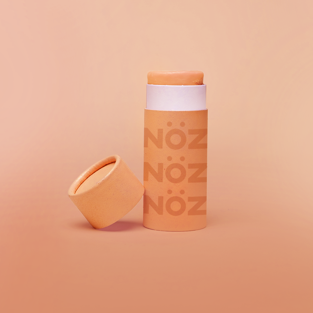 Orange Noz sunscreen standing with cap leaning on container