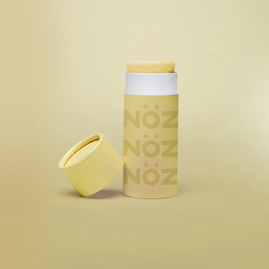 Yellow Noz sunscreen standing with cap leaning on container